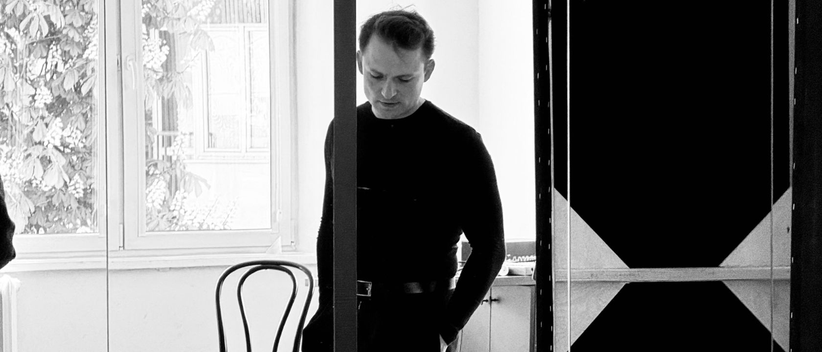 mężczyzna aktor ubrany na czarno odbija się w lustrze podczas próby spektaklu, patrzy w dół, zdjęcie z pierwszej próby do spektaklu król komedii