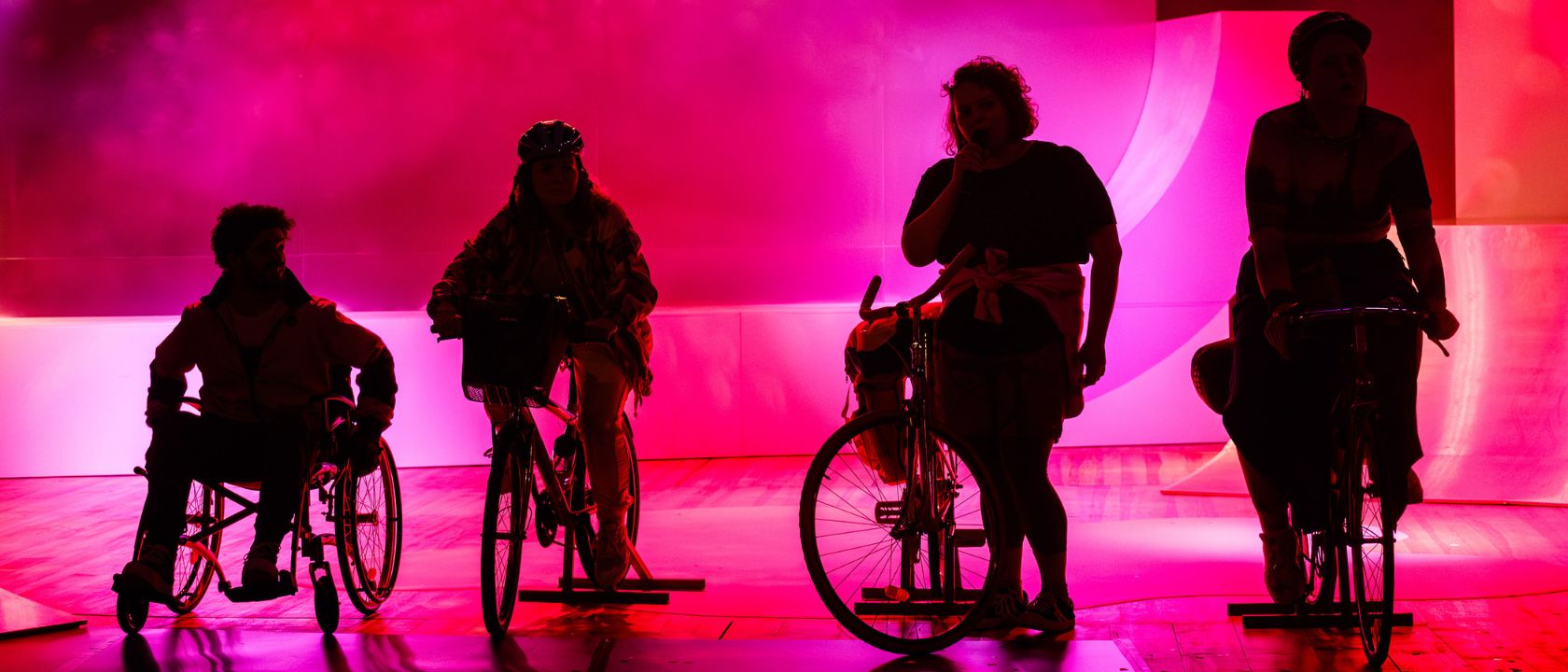 na scenie teatralnej stoją przy rowerach cztery osoby, widać tylko ich cienie