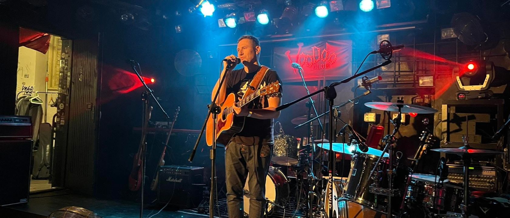zdjęcie z koncertu, na fotografii artysta z gitarą przy mikrofonie