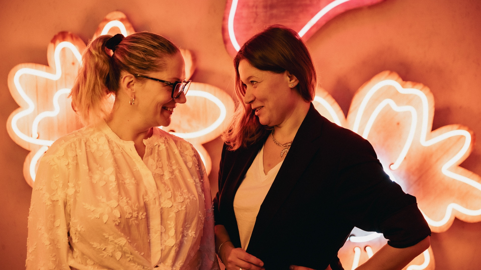 zdjęcie przedstawia dwie kobiety uśmiechające się do obiektywu