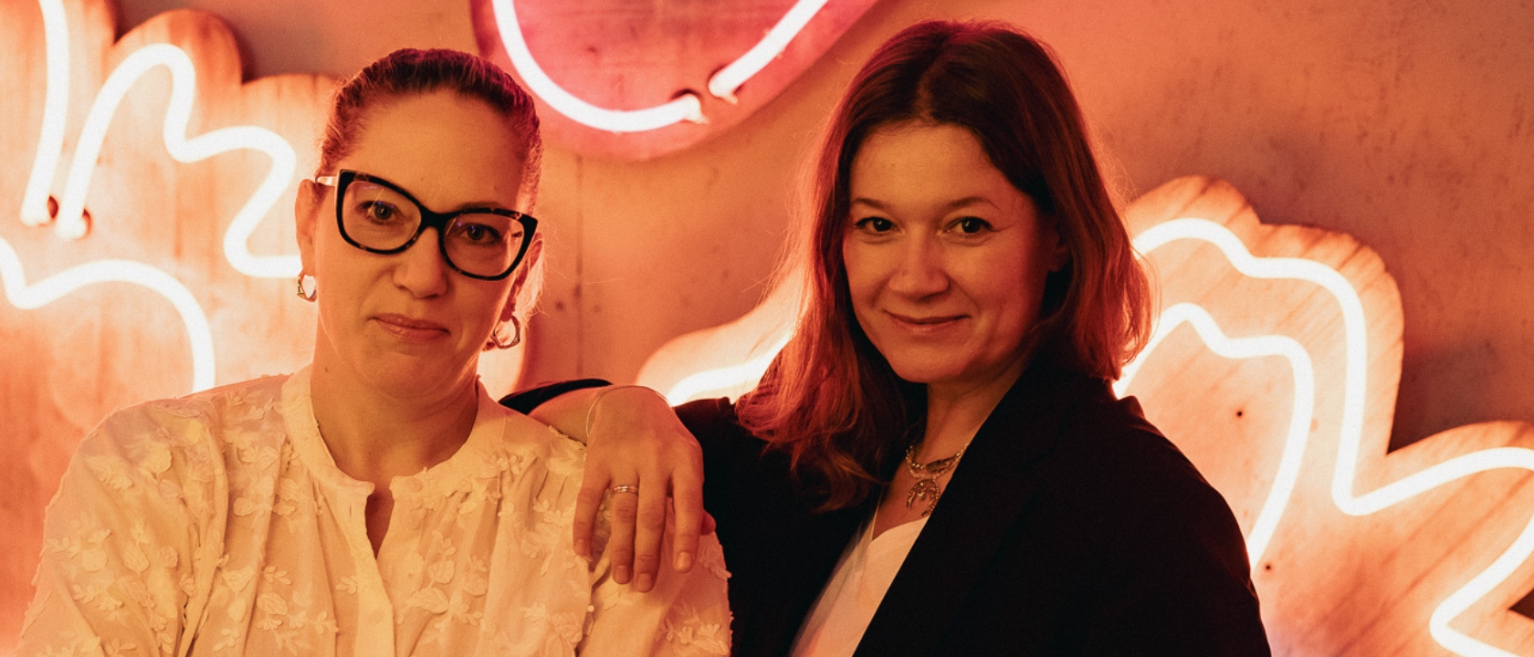 zdjęcie przedstawia dwie kobiety uśmiechające się do obiektywu