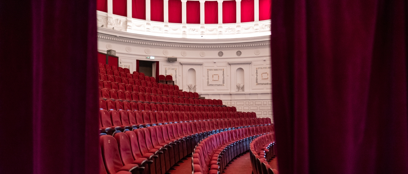 zdjęcie przedstawia teatralną widownię, widać rzędy foteli i sklepienie teatru