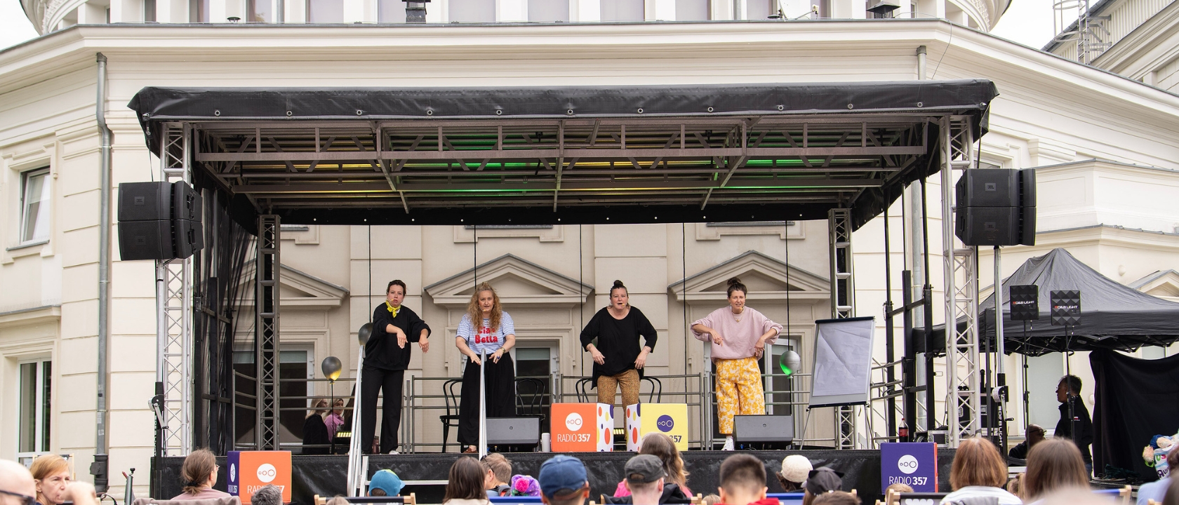 zdjęcie przedstawia scenę plenerową Teatru Komedia, na scenie kilka osób, przed sceną widzowie